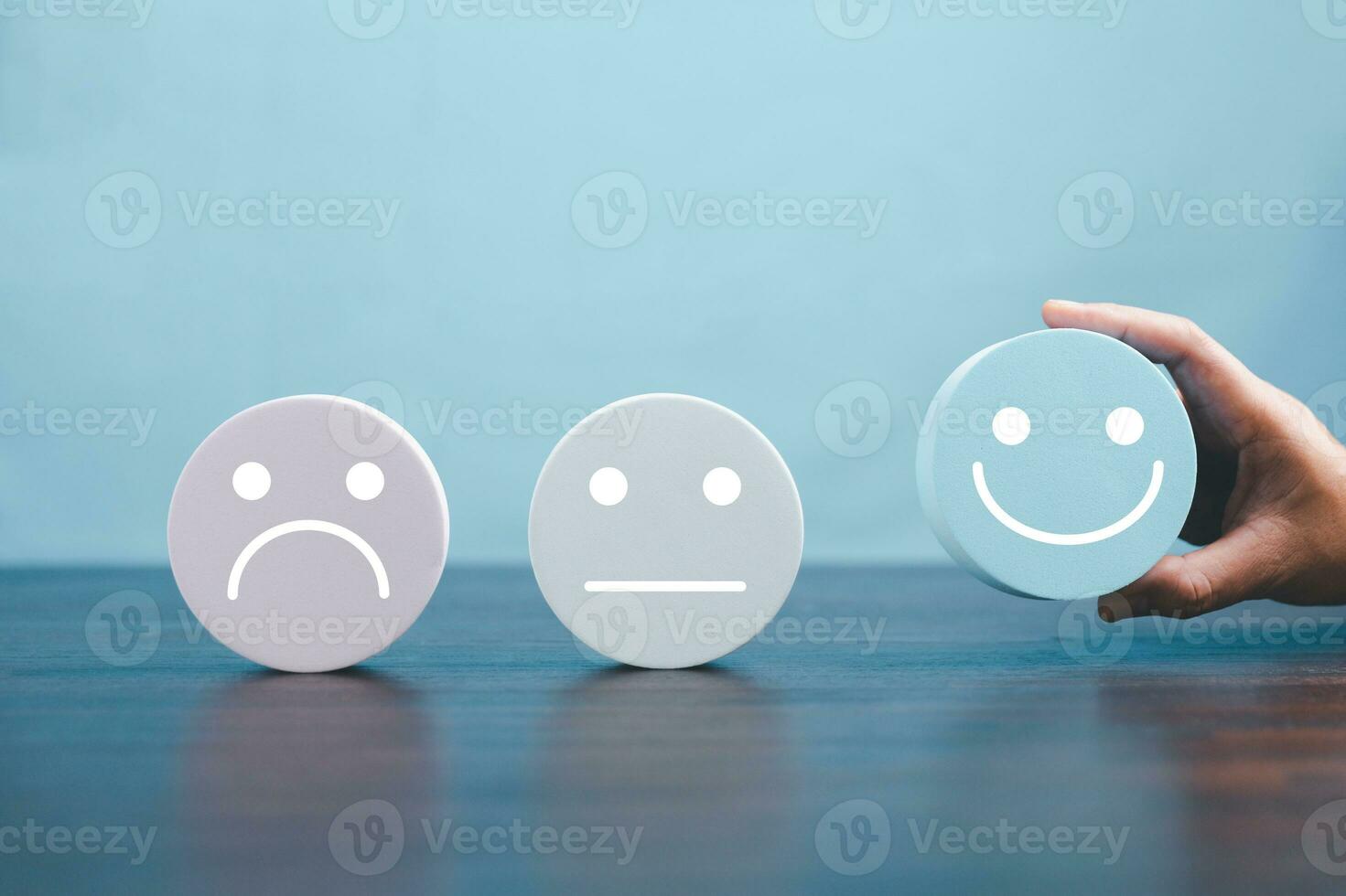 Woman hand holding happy face smile face icon on round blue object. Customer experience and service with satisfaction concept. positive thinking, mental health assessment, world mental health day. photo