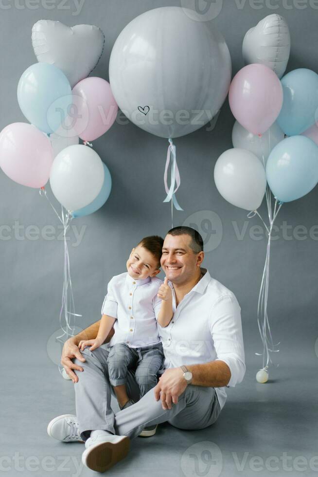 A stylish father with his four-year-old son on the background of balloons, celebrating a birthday or father's day photo