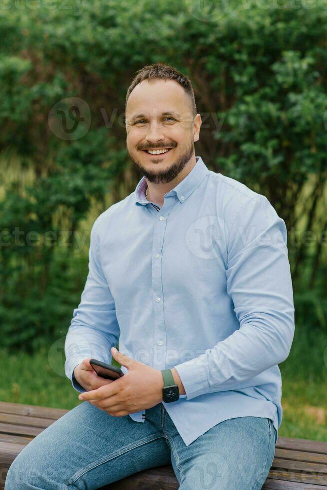 hermoso hombre sonriente con móvil teléfono al aire libre foto