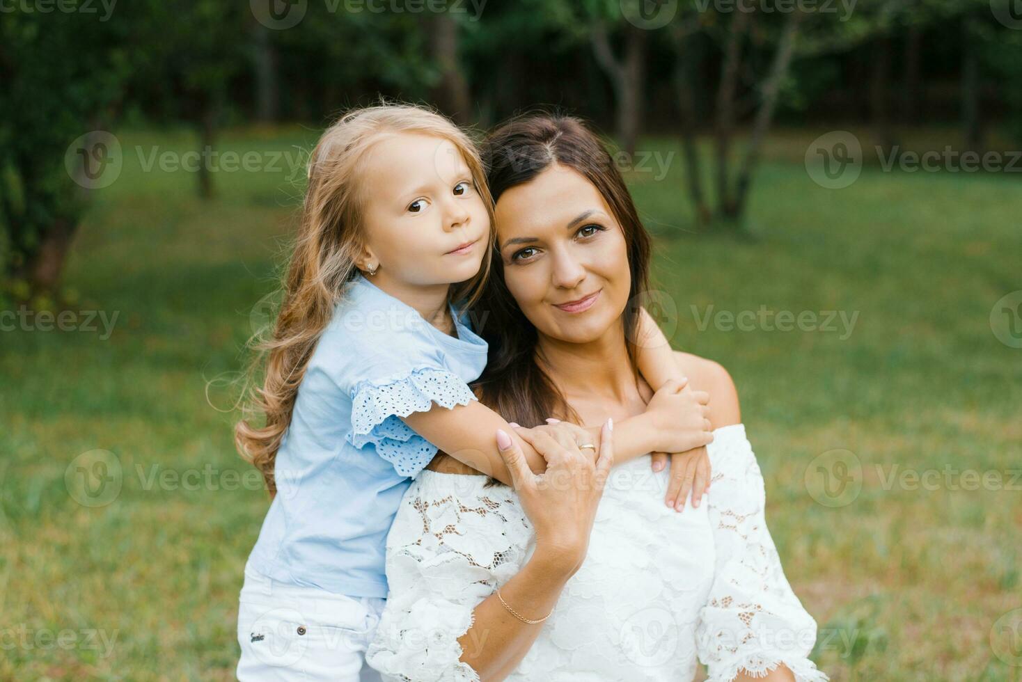 Five-year-old daughter hugs her mother's neck photo