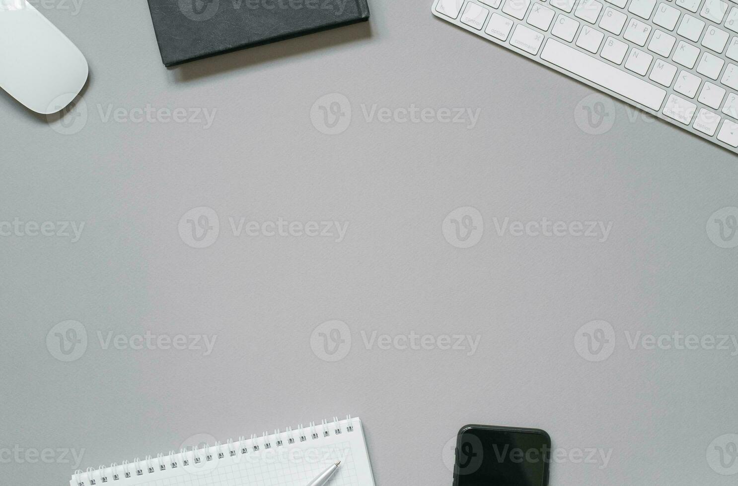 Workplace of an office worker or freelancer keyboard, mouse, gliders and diaries, ballpoint pen, phone on a gray background with copy space. photo