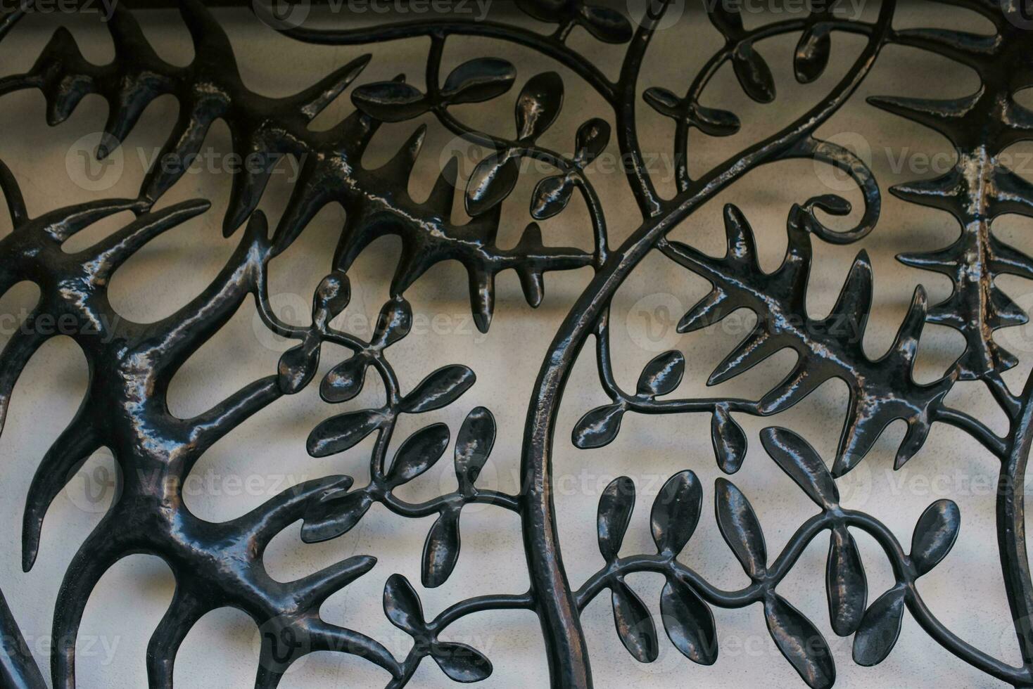 A metal grill in the form of a tree branch with black leaves on a light gray background. Original background for copy space. photo