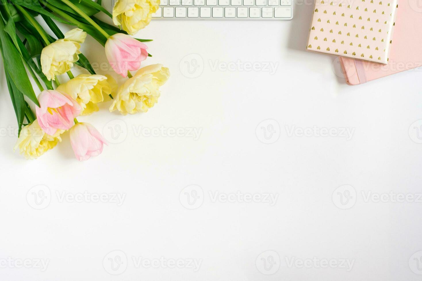 Springtime flat fly with keyboard, notebooks, bunch of pink tulips on a light background. Spring concept for a blog. Greeting Card for Valentine's Day or Mother's Day photo