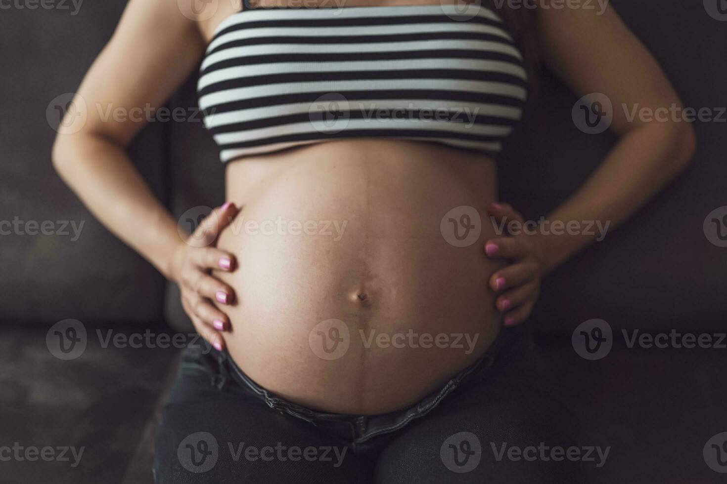 Pregnant woman relaxing at home. She is sitting on bed in bedroom. photo
