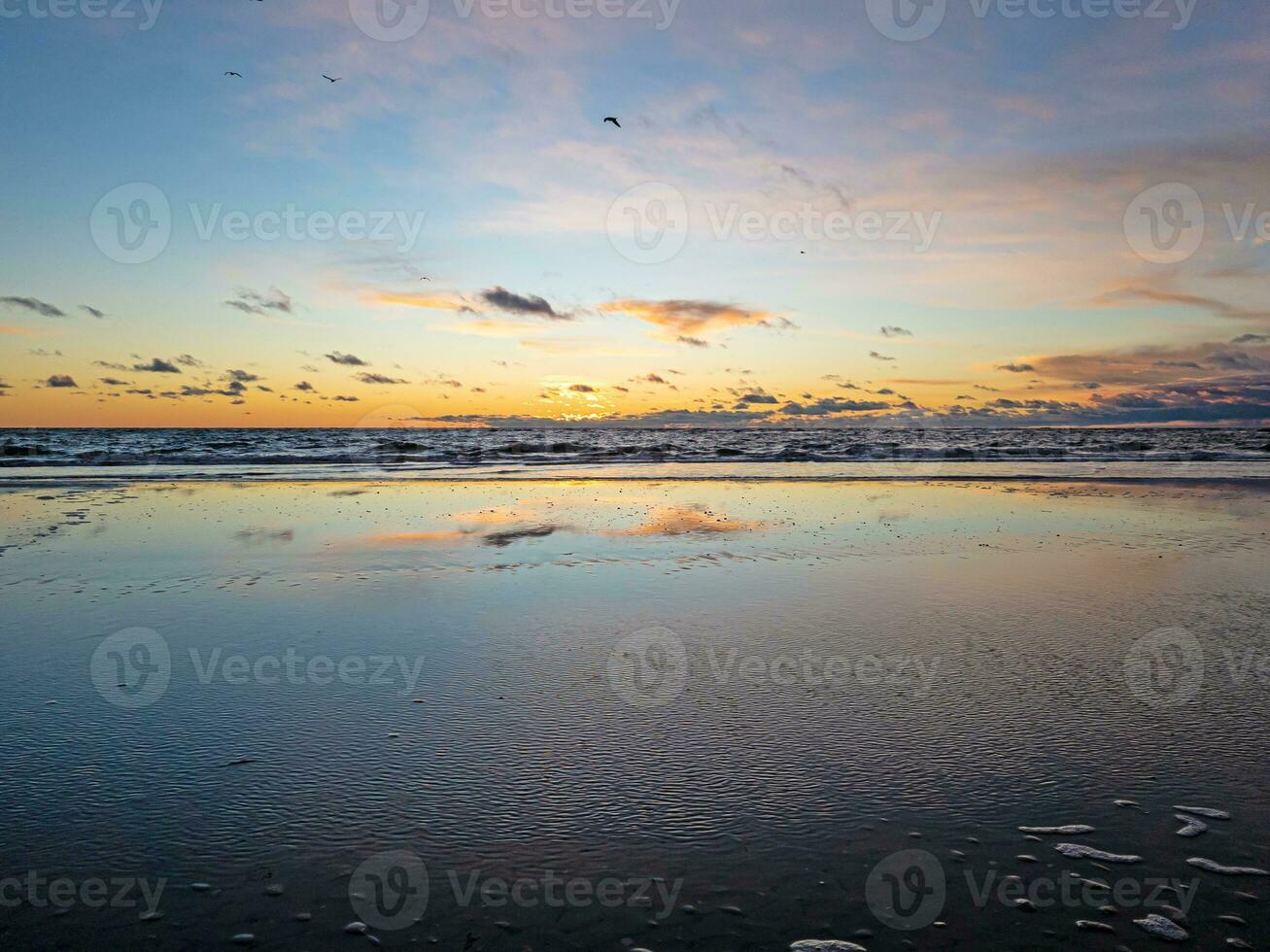 Sunset over the sea with reflections in the rising surf photo