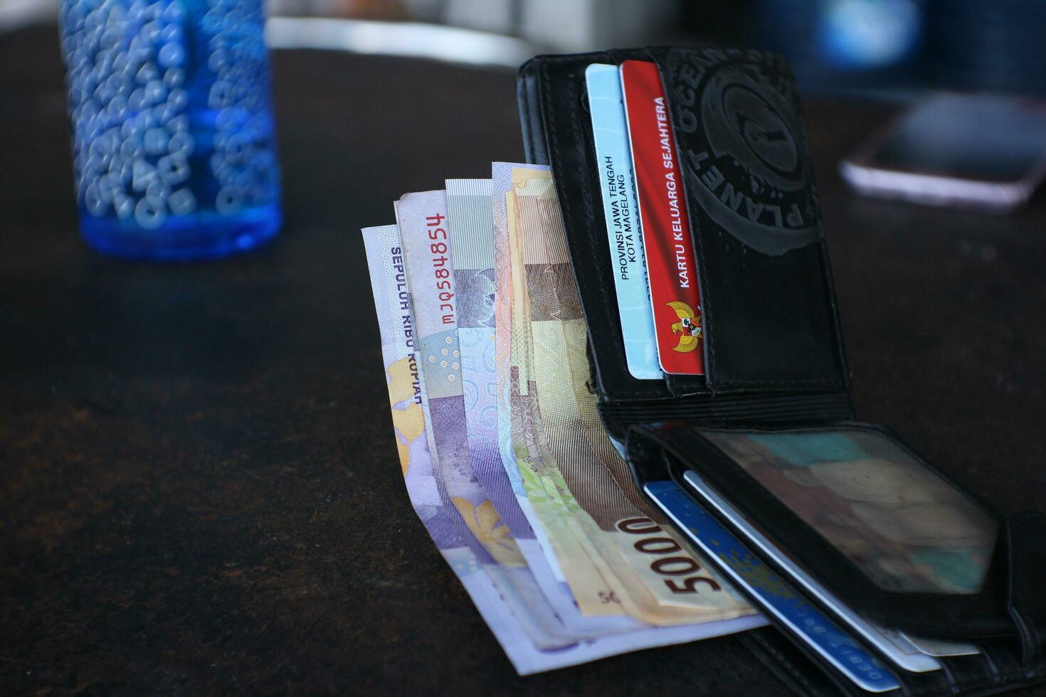 Magelang 23,05,2023- Poor man holding small Indonesian Rupiah notes in his black leather wallet. photo
