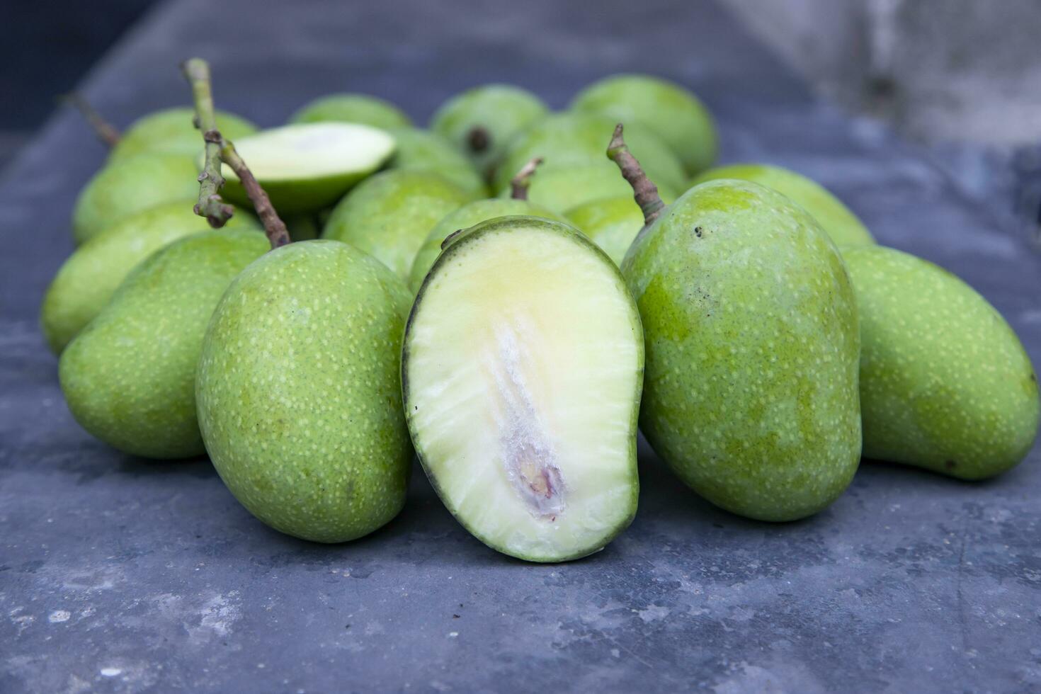 Closeup focus Fresh Raw  Mango with sliced mango on the concrete floor. Pickle ingredient photo