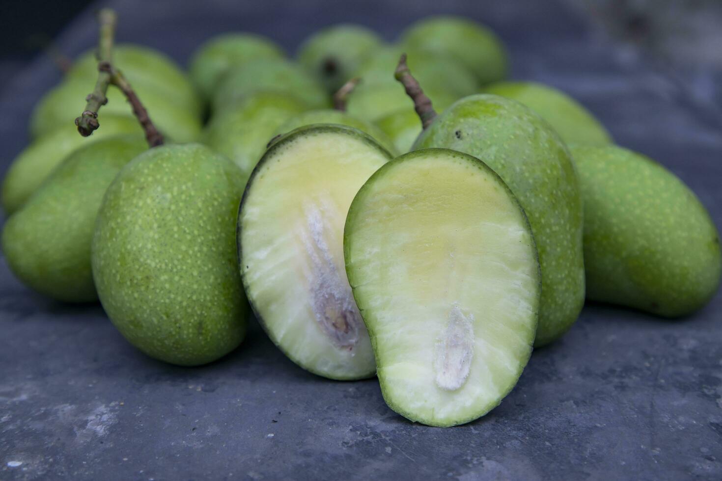 Closeup focus Fresh Raw  Mango with sliced mango on the concrete floor. Pickle ingredient photo