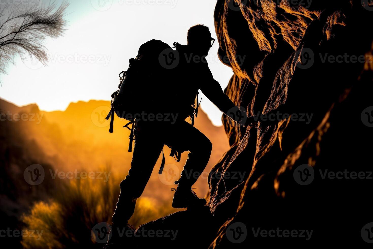 male climber climbing mountains dark silhouette against the background of the sun photo