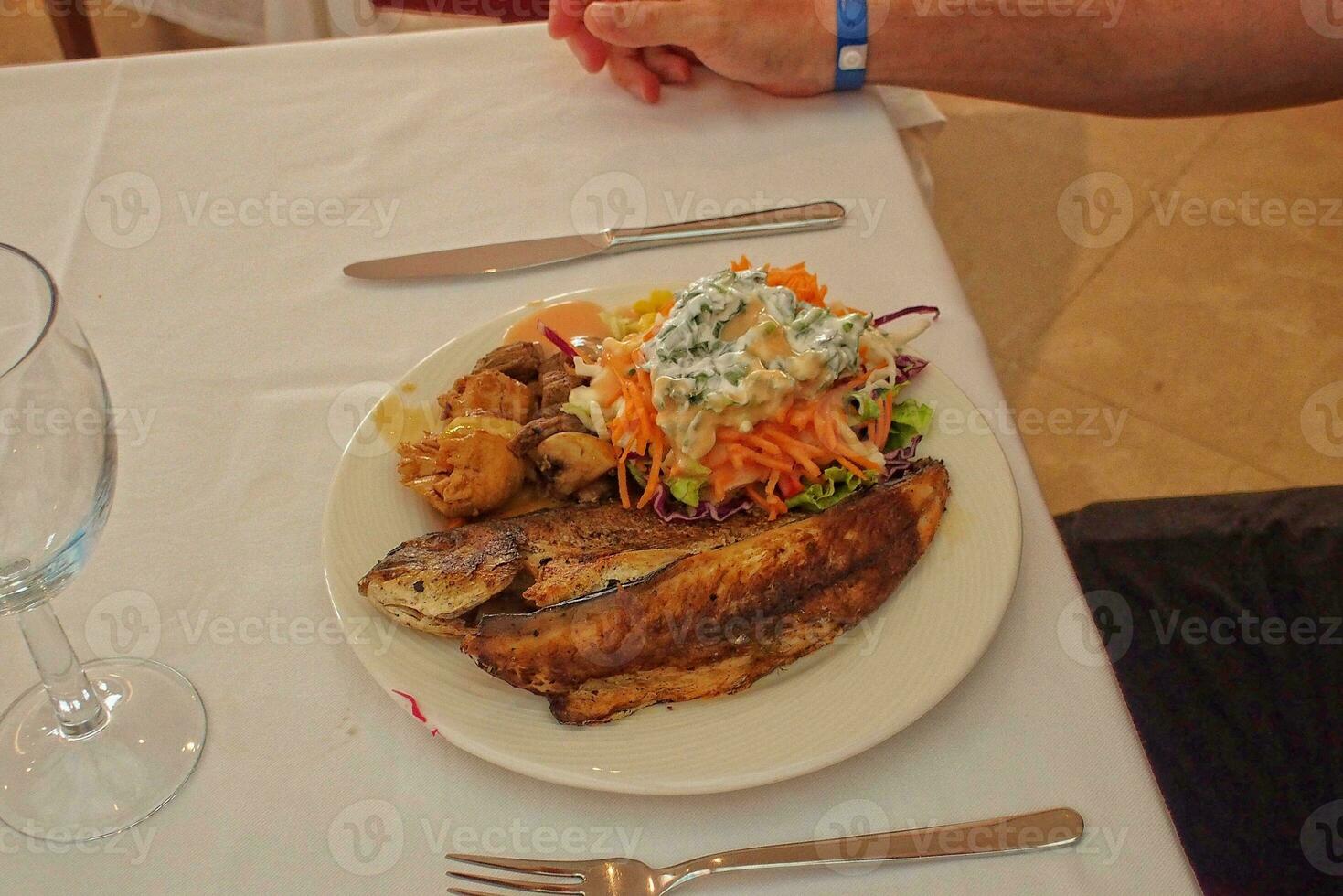 tasty big grilled fish on a white plate with vegetables photo