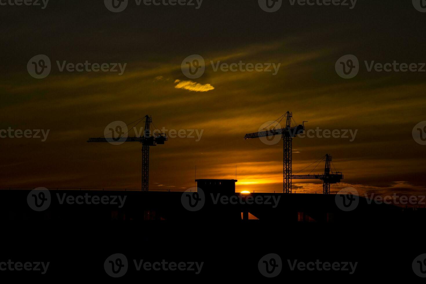 picturesque sunset with clouds in the sky in the city with construction cranes, photo