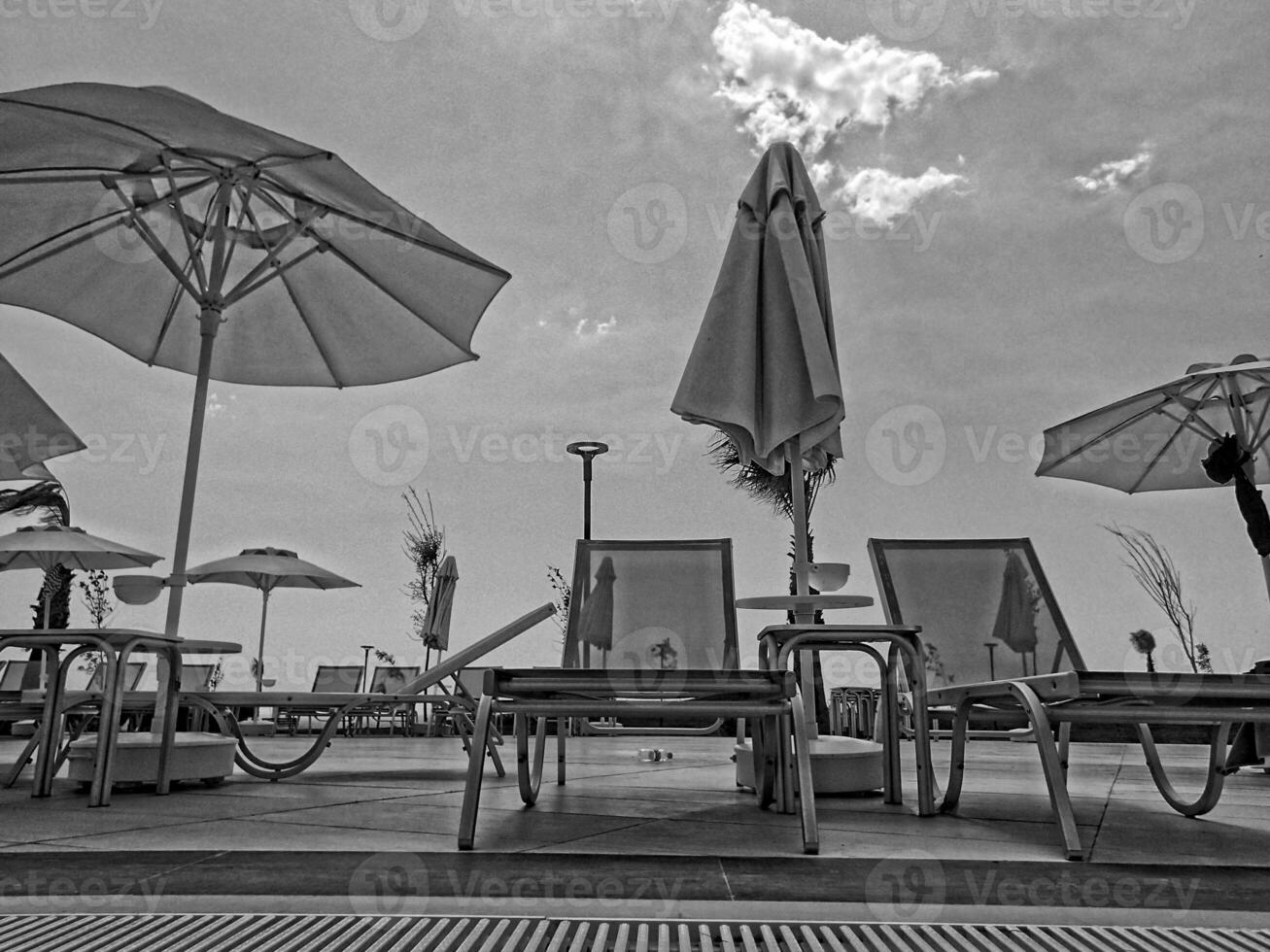 calm landscape over the pool with sunbeds, palm umbrellas and blue cloudless sky photo