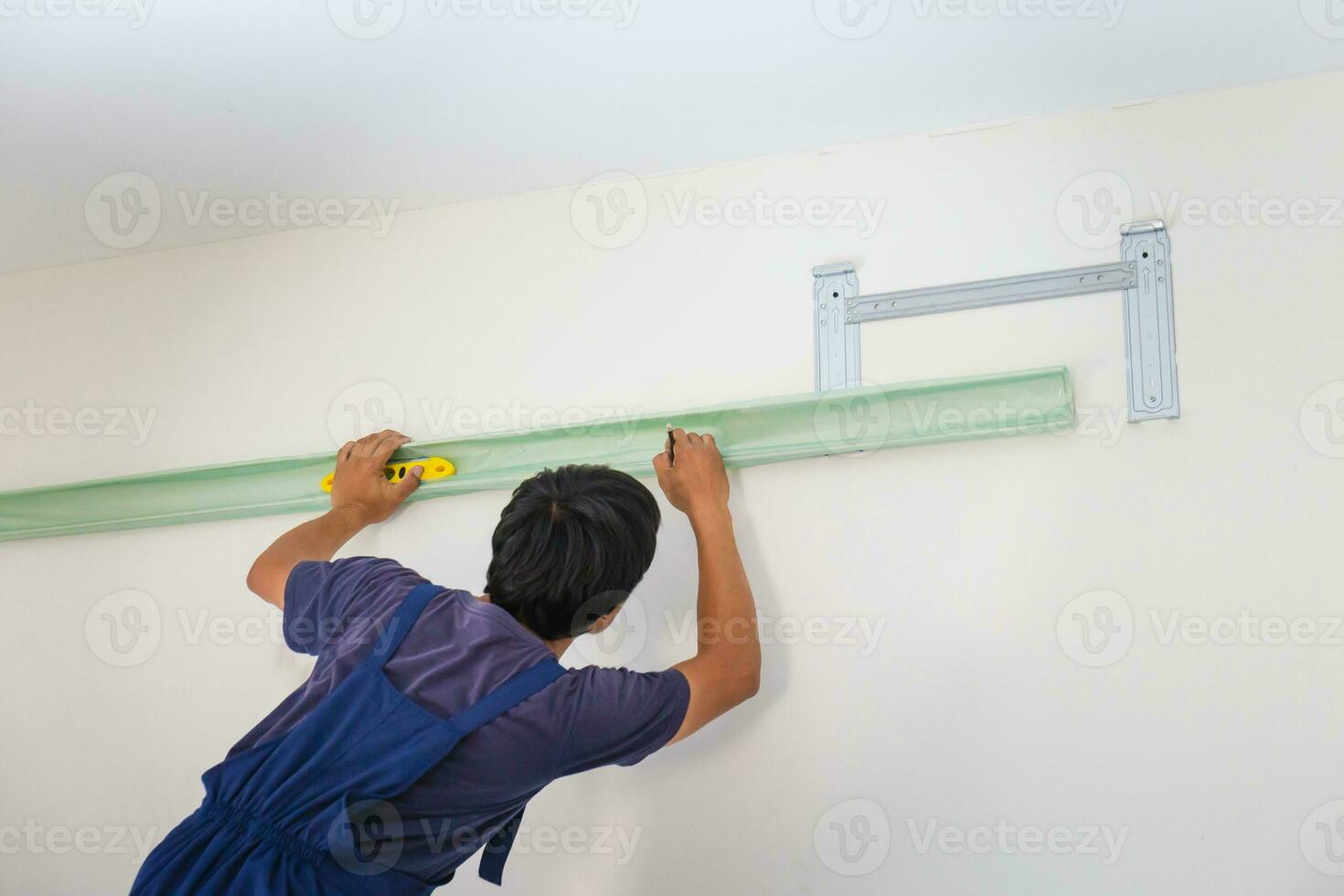 Young repairman fixing air conditioner unit, Asian technician man installing an air conditioning in a client house, Maintenance and repairing concepts photo