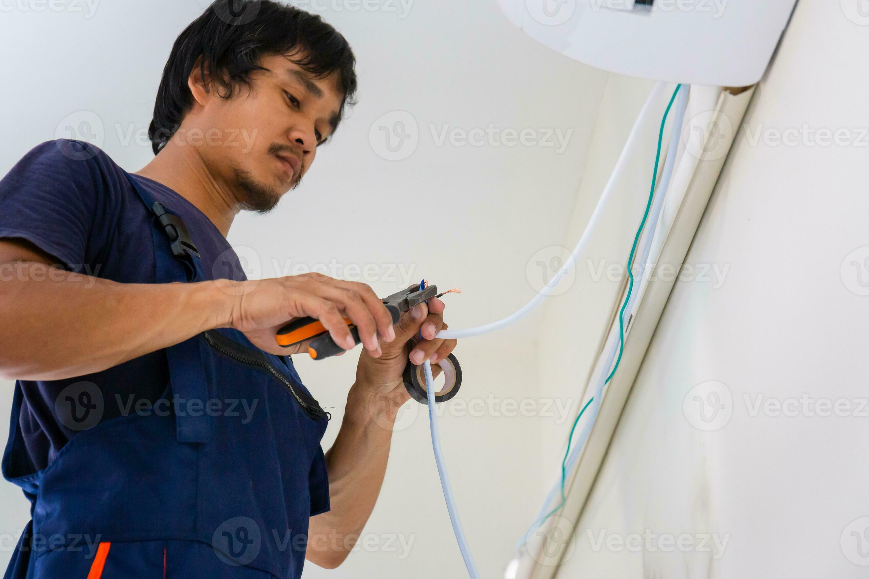 Electrician mounting the wires into air conditioning unit, Technician