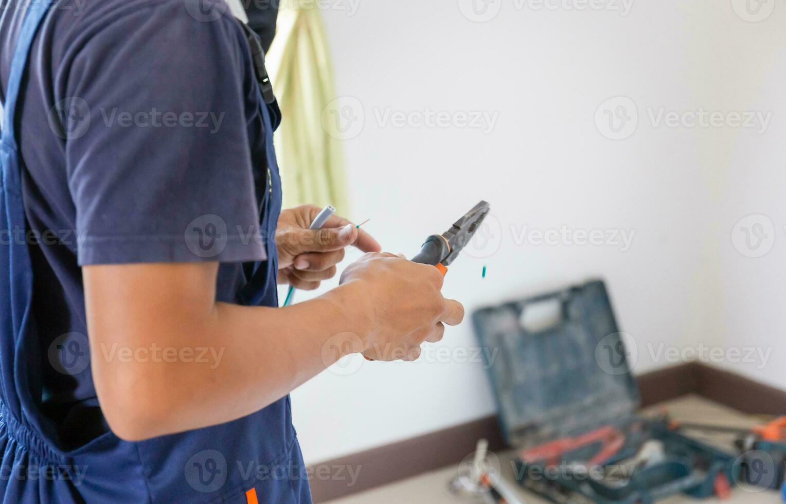 Electrician cuts electrical wires with pliers, Technician installing air conditioning in a client house, Repairman fixing air conditioner unit, Maintenance and repairing concepts photo