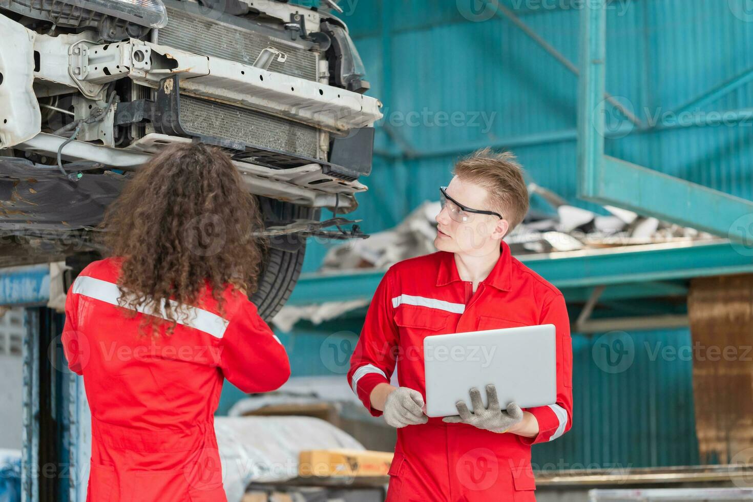 joven mecánica equipo en uniforme son trabajando en auto Servicio con levantado vehículos coche reparar y mantenimiento conceptos foto