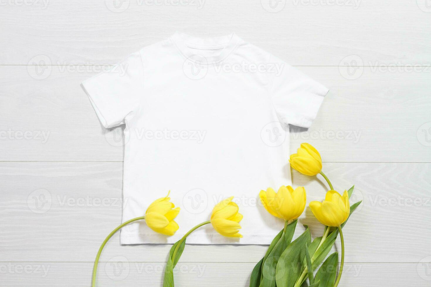 White children t-shirt mockup. Template blank kids shirt top view. White wooden background. Mother women day holiday. Yellow tulip. Baby tshirt with birthday flower. Spring look. photo