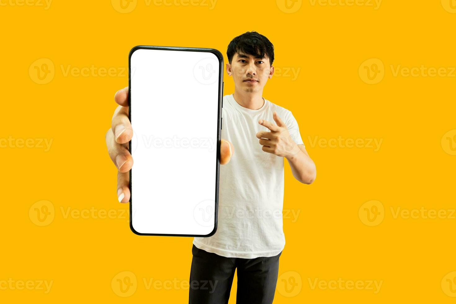 Asian Man Hand Pointing At Empty White Smartphone Screen on yellow Background. Cellphone Display Mock Up For Mobile App Advertisement. photo