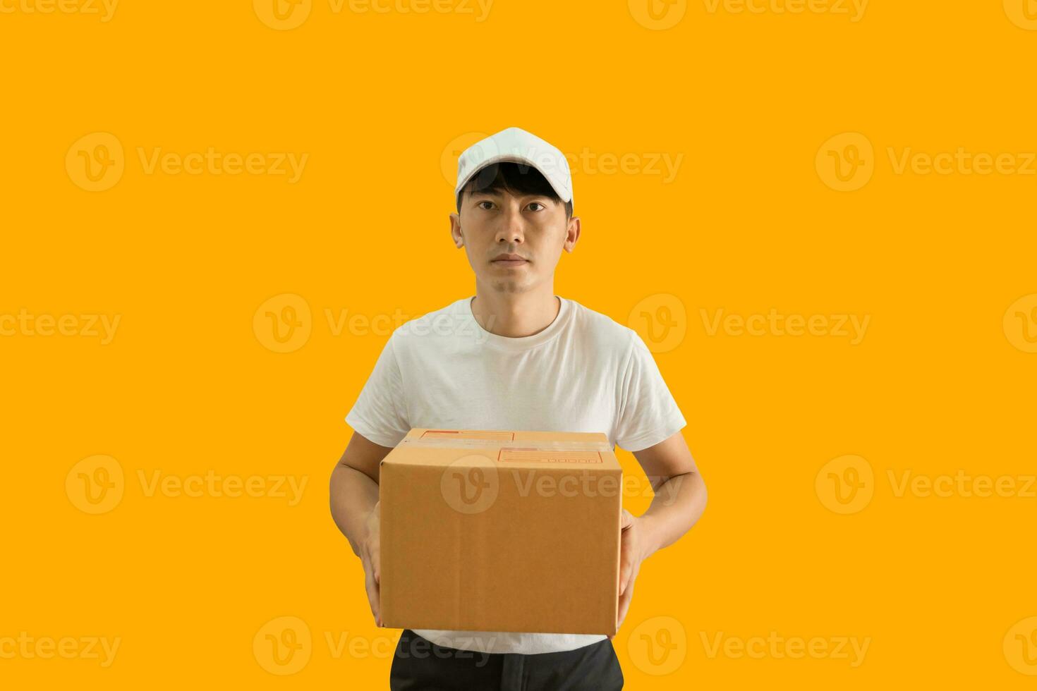 joven asiático entrega hombre vistiendo gorra y blanco blanco camiseta participación paquete o empaquetar enviar caja aislado en amarillo antecedentes. Rápido entrega Servicio concepto. foto