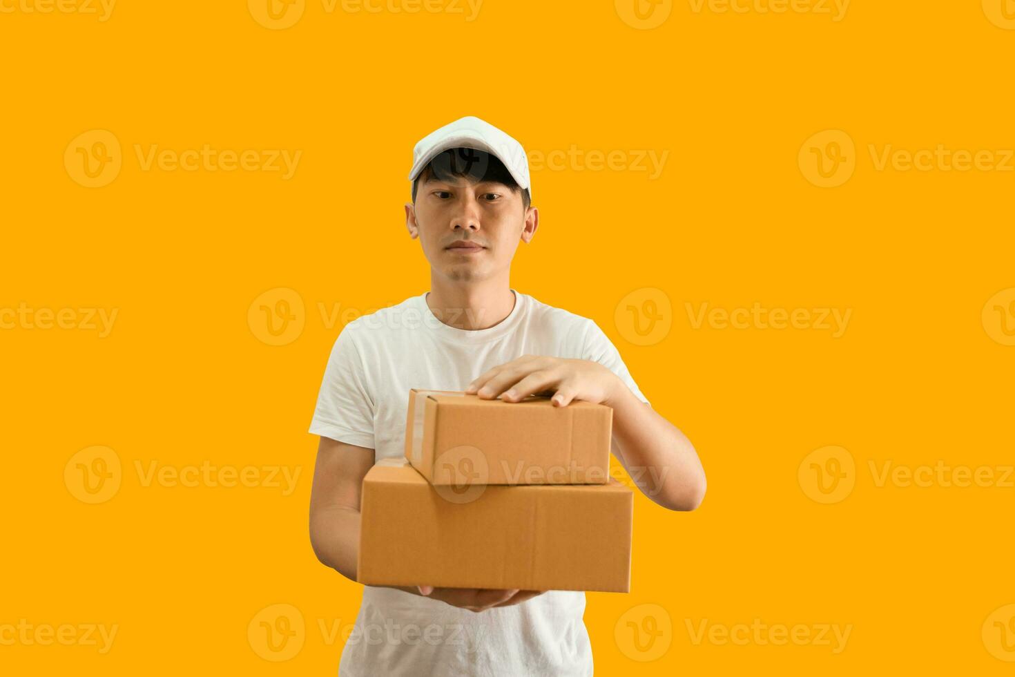 joven asiático entrega hombre vistiendo gorra y blanco blanco camiseta participación paquete o empaquetar enviar caja aislado en amarillo antecedentes. Rápido entrega Servicio concepto. foto