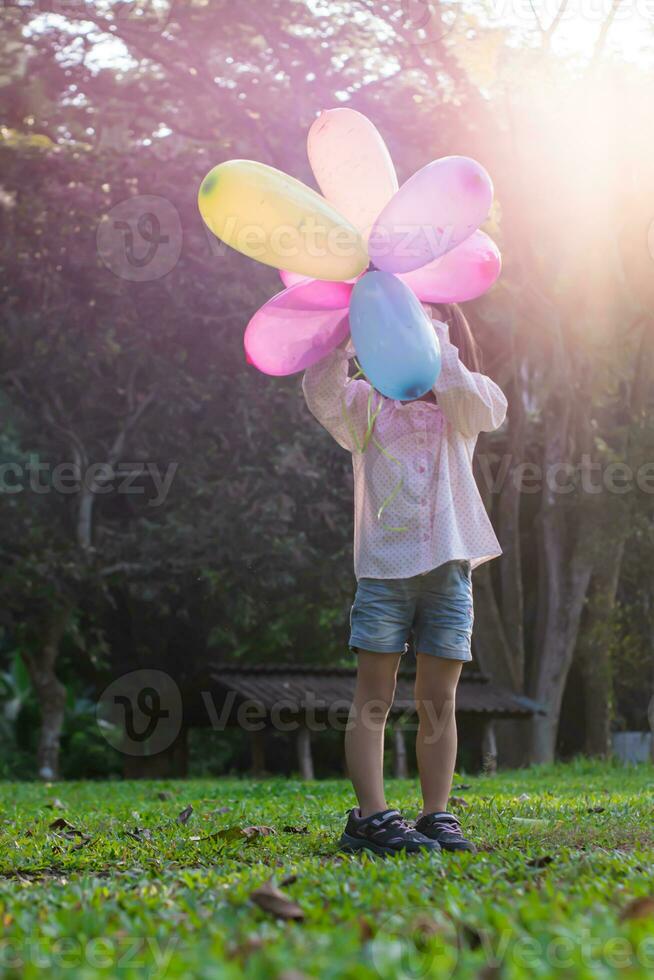 Portrait of child girl playing with colorful toy balloons in the park outdoors. photo