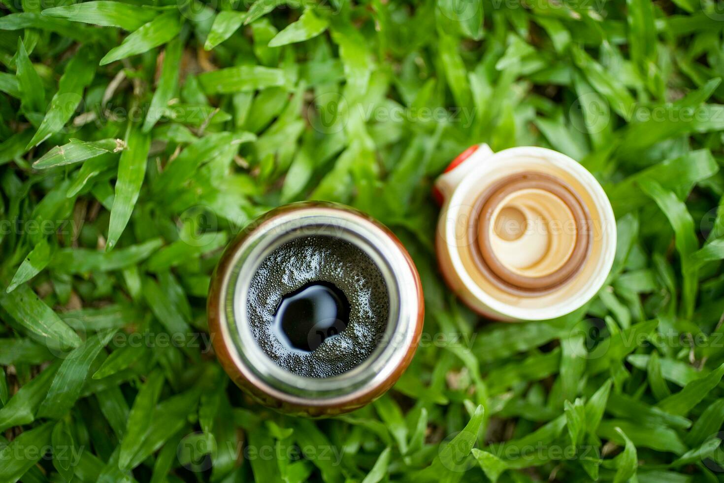 Black coffee in a thermos on the green grass,  selective focus, and soft focus. photo