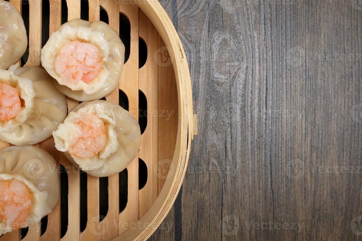 Prawn shrimp shaomai dim sum dumpling in bamboo steamer on rustic wood background photo
