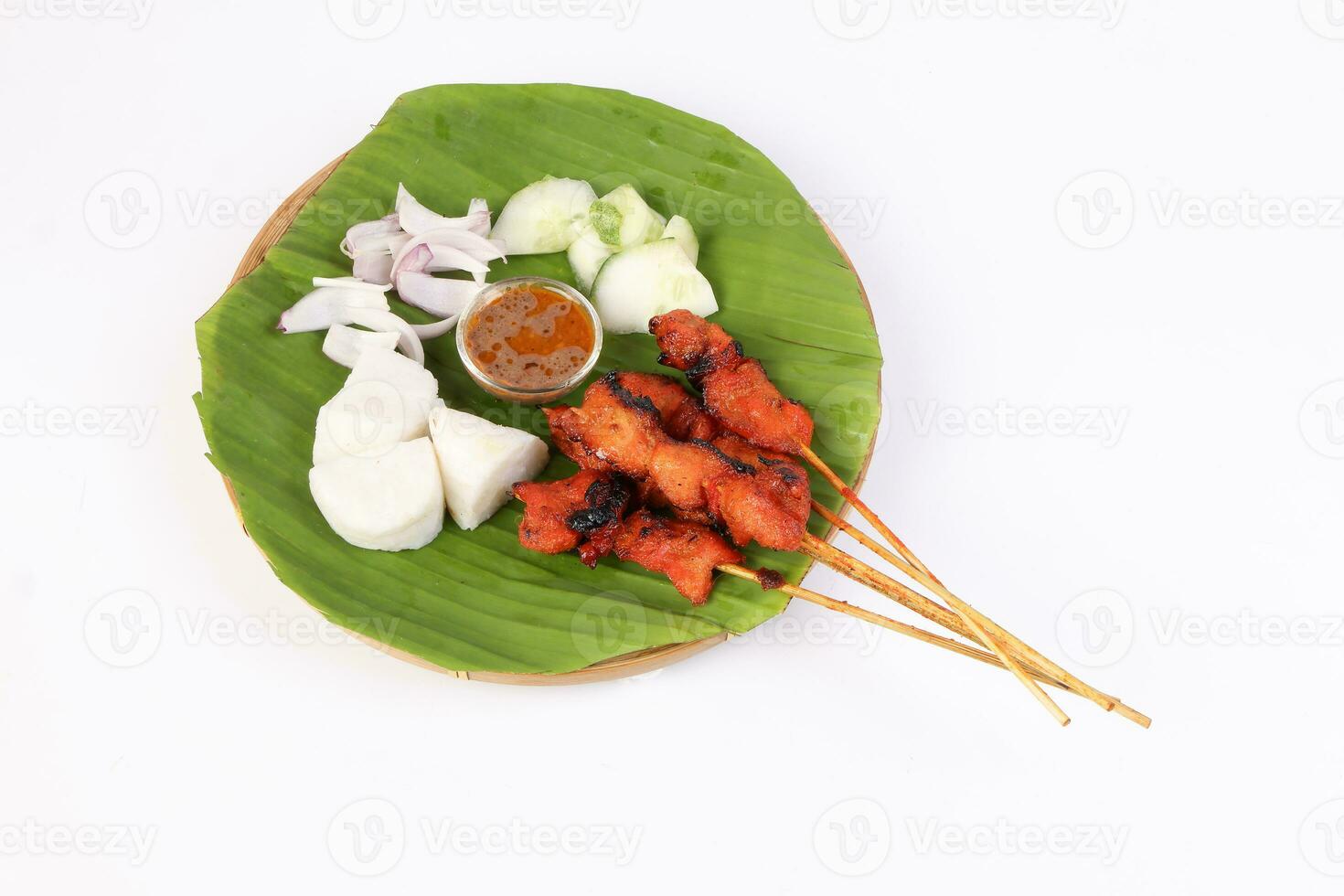 Chicken beef mutton meet Satay set nasi impit sticky rice cake sliced onion cucumber sweet peanut sauce on banana leaf bamboo basket on white background photo