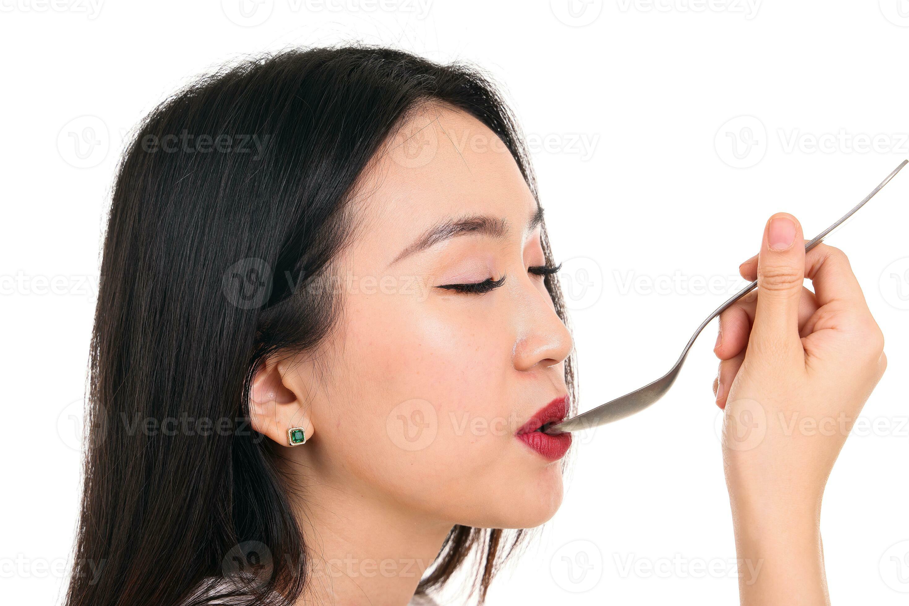 Beautiful young south east Asian woman pretend acting posing holding empty spoon in hand on lips
