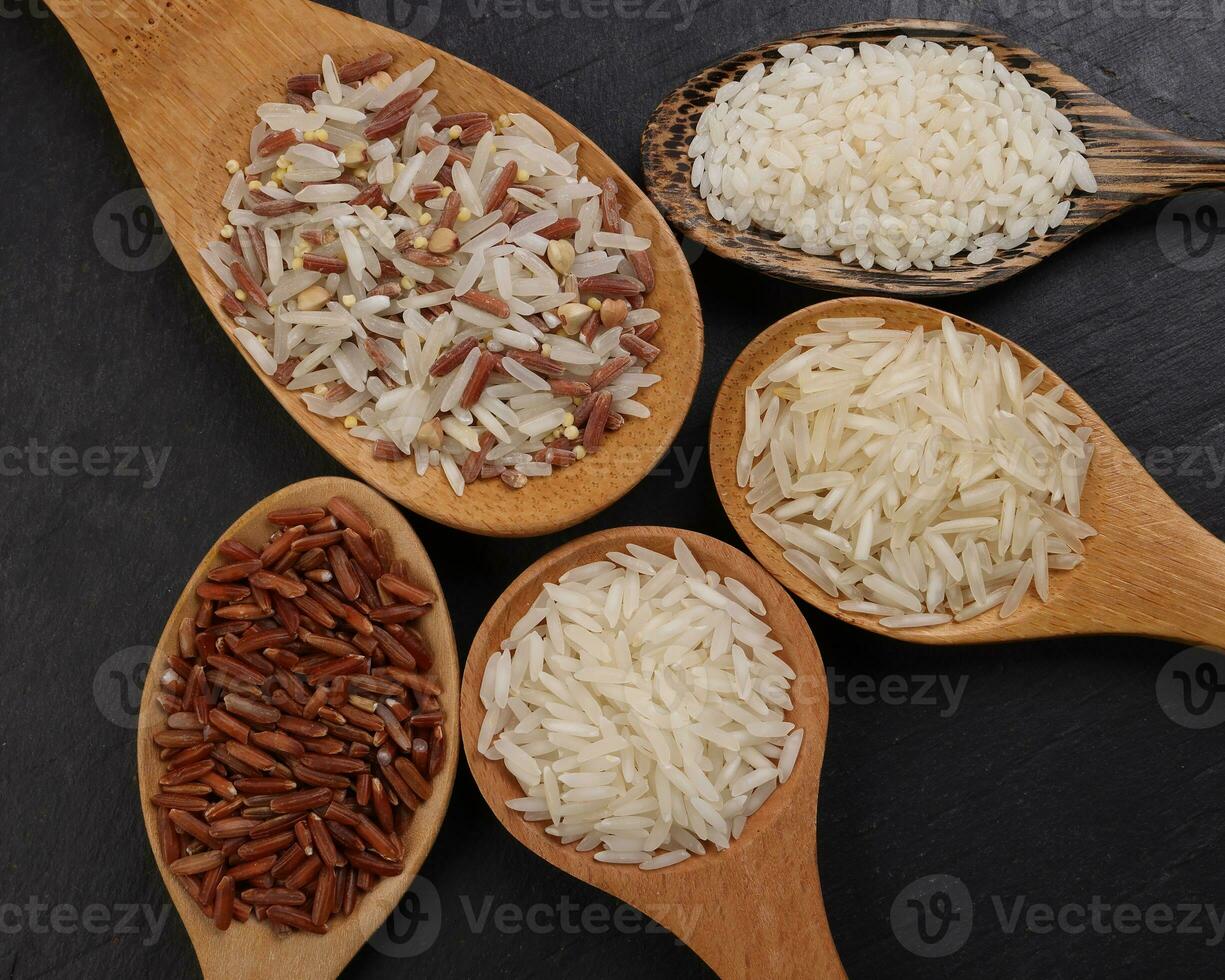 Long grain basmati medium grain jasmine short grain pilaf polau risotto brown low glycaemic index gi rice in wooden spoon on black background copy text space top flat lay view photo