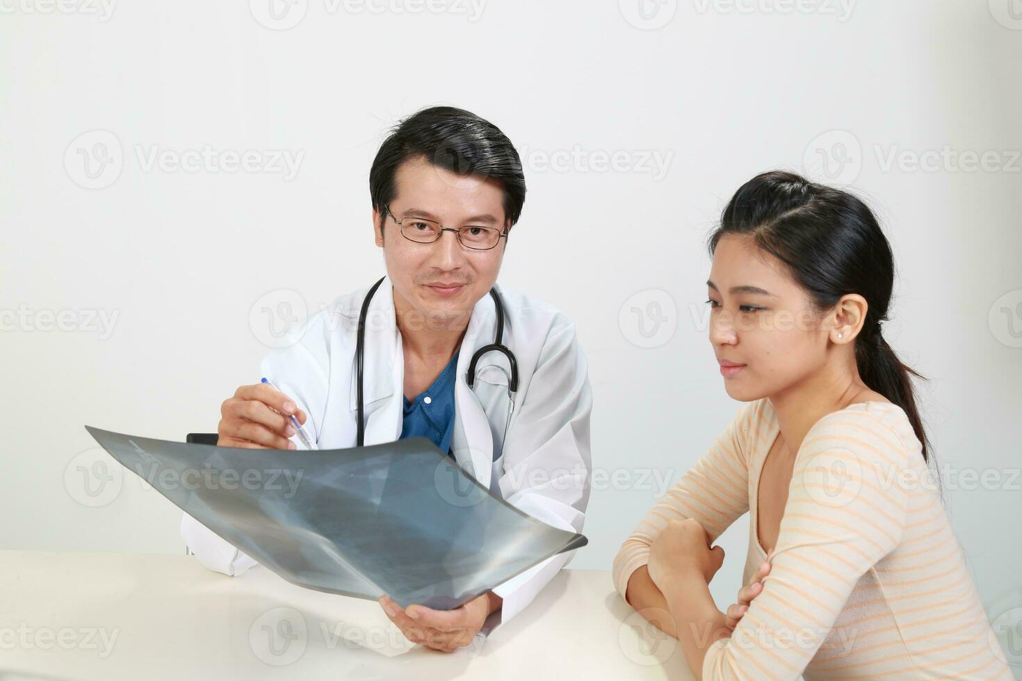 Young Asian male doctor wearing apron uniform stethoscope female patient talk discuss cheek photo
