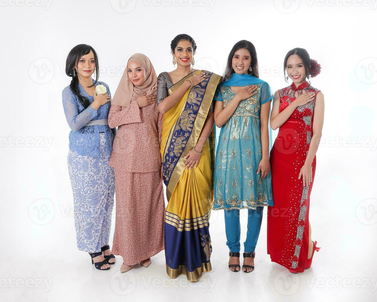 South east Asian Malay Chinese Indian race ethnic origin woman wearing dress costume baju kurung cheongsam samfu kebaya Sharee multiracial community on white background welcome hand on chest photo