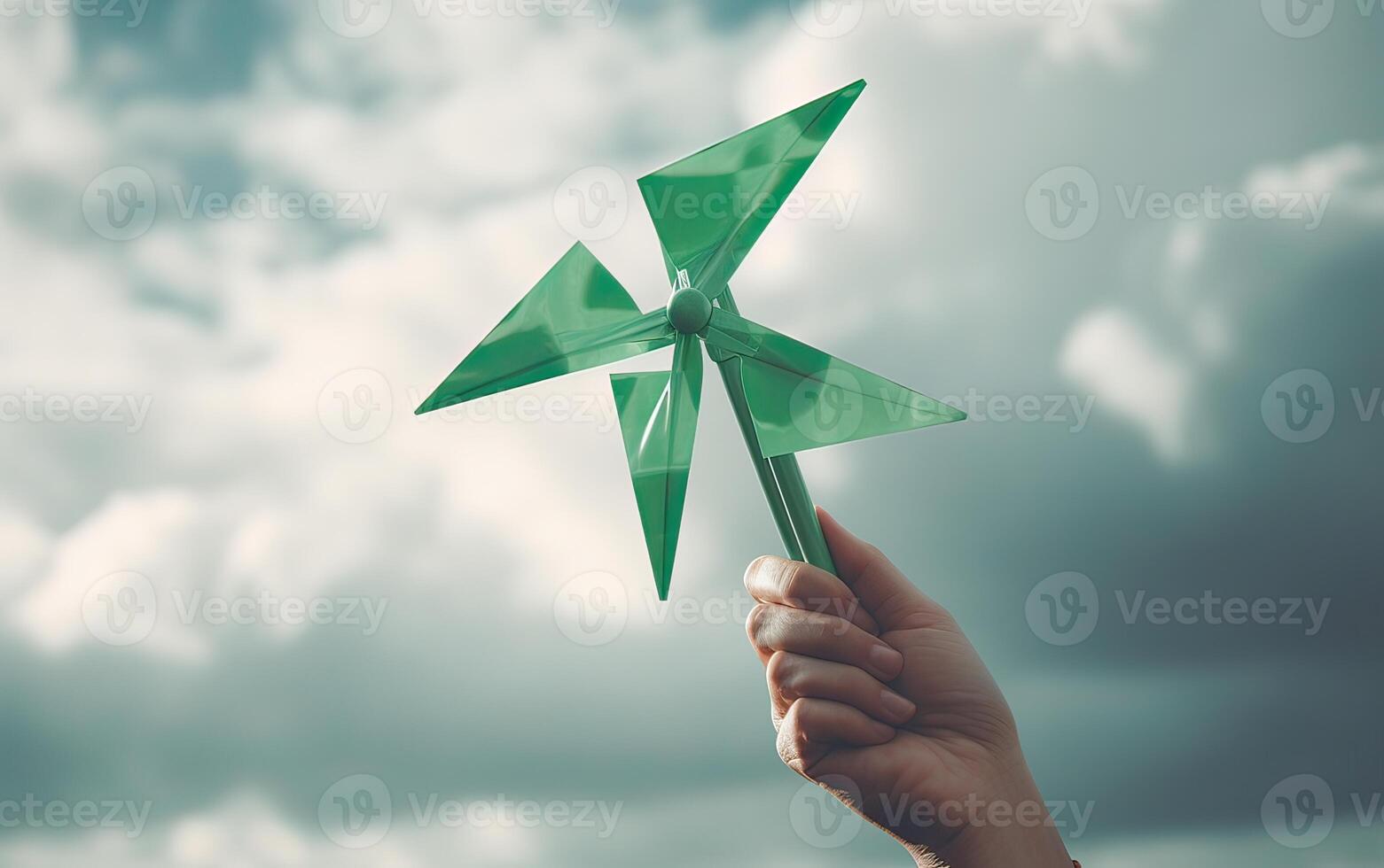 hand holding a green pinwheel in one hand. Hand holding a green pinwheel with blue sky background. . photo