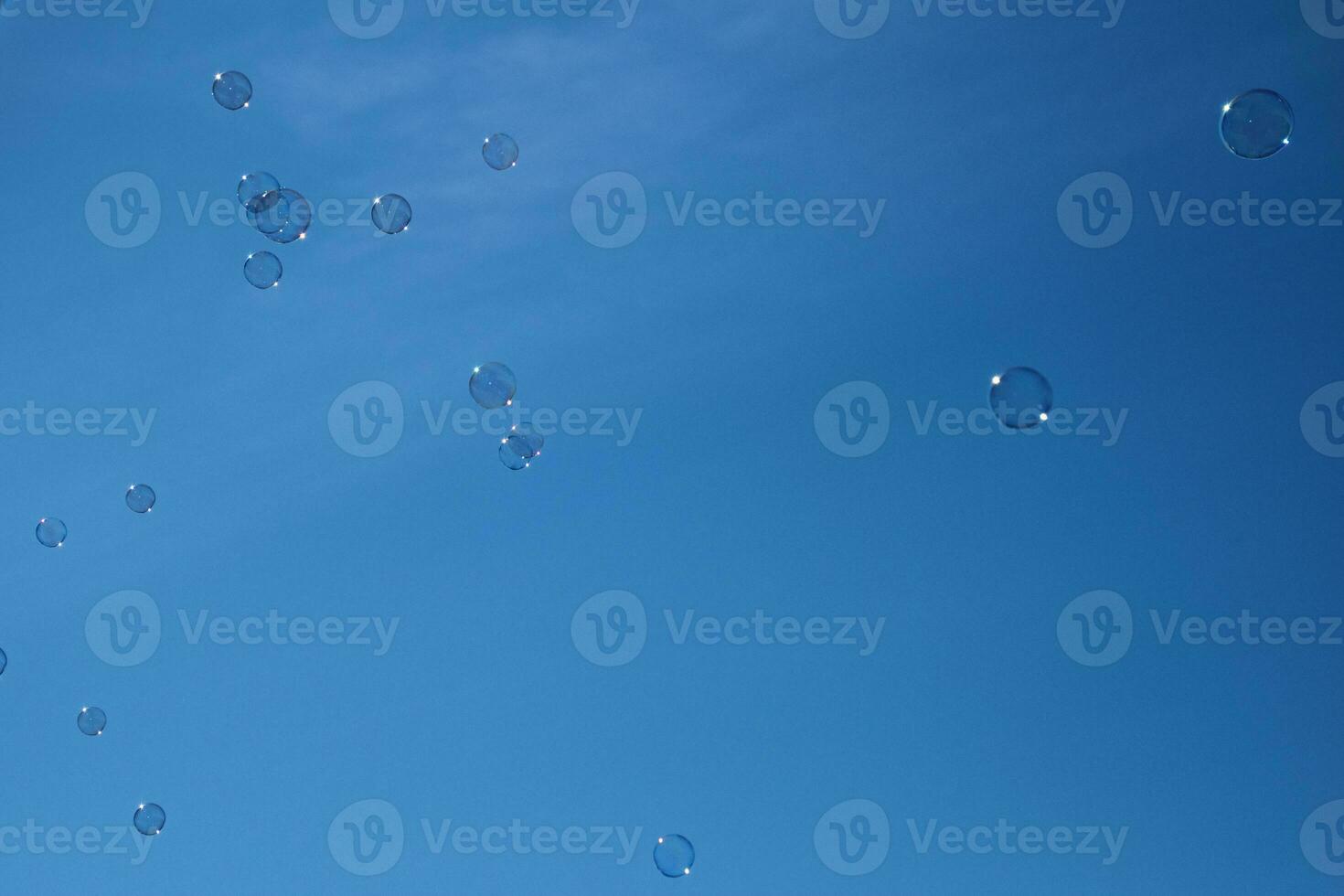 delicate fragile soap bubbles flying against the background of a blue cloudless sky on a summer day, photo