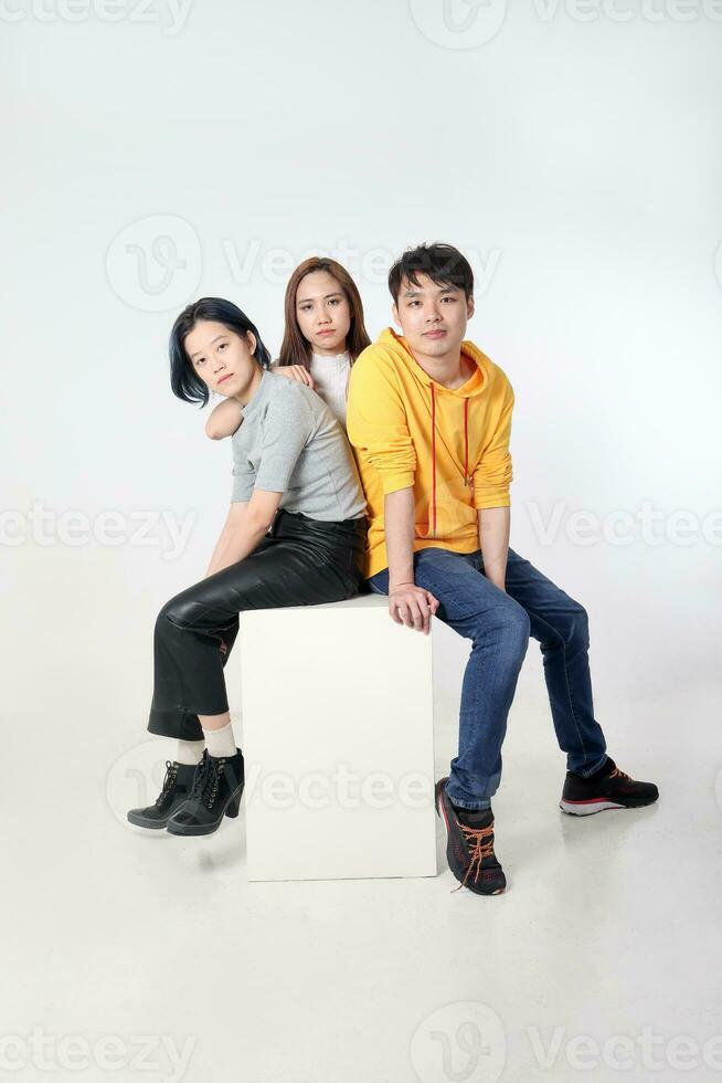 Group of young south east asian mixed race man woman chinese malay sit on box pose white background moody relax fashion students colleagues look at camera photo