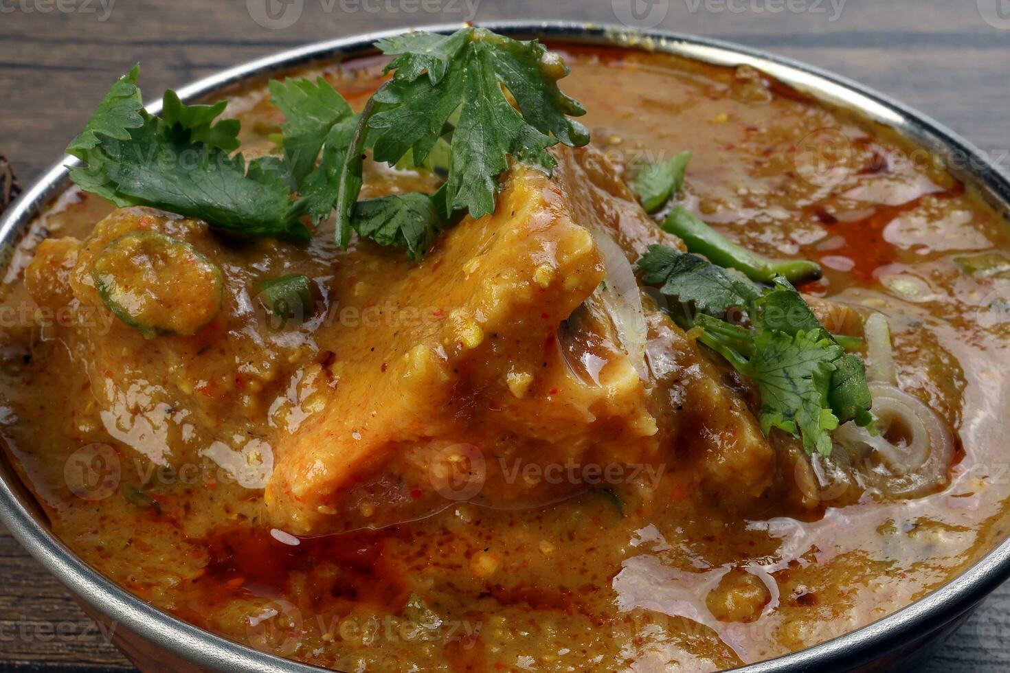 Haleem stew wheat barley lentils mutton goat chicken beef meat bone spice served in a copper brass pot over rustic wood background photo