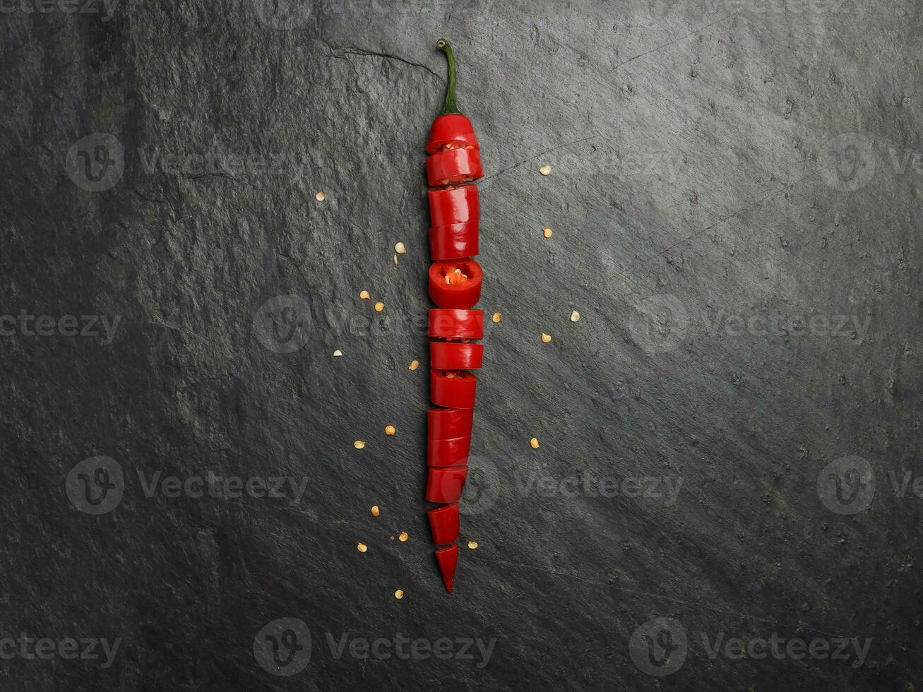 Red hot chilli pepper on dark black rough slate stone surface background photo