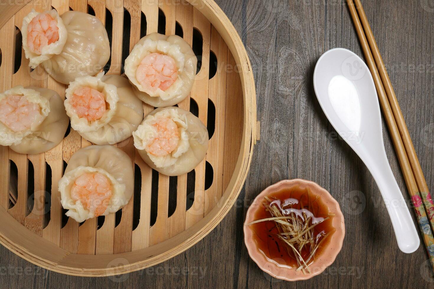 Prawn shrimp shaomai dim sum dumpling in bamboo steamer sauce chopsticks soup soon on rustic wood background photo