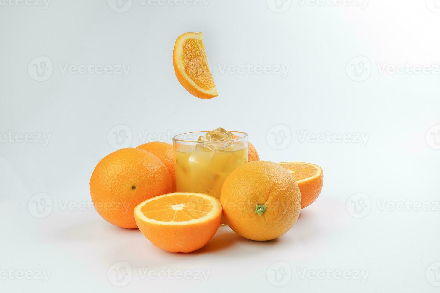Fresh yellow orange juice in glass with whole floating sliced orange fruit and ice cube on white background photo