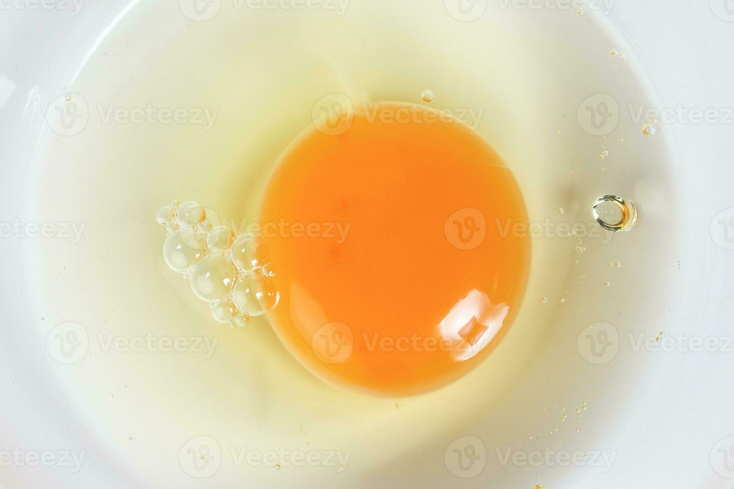 Raw Egg Yolk and white liquid in transparent glass bowl white background photo