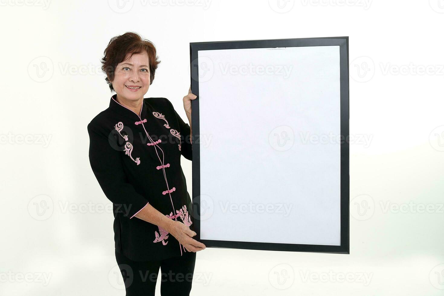 Elderly asian Chinese female wearing black tang samfu on white background holding white black board copy text space photo