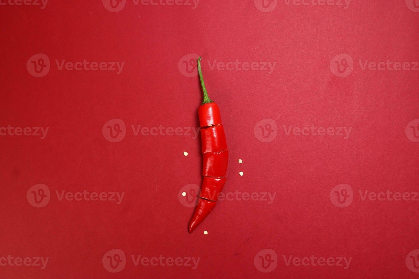 red chilli pepper on red paper background cut pieces seeds photo