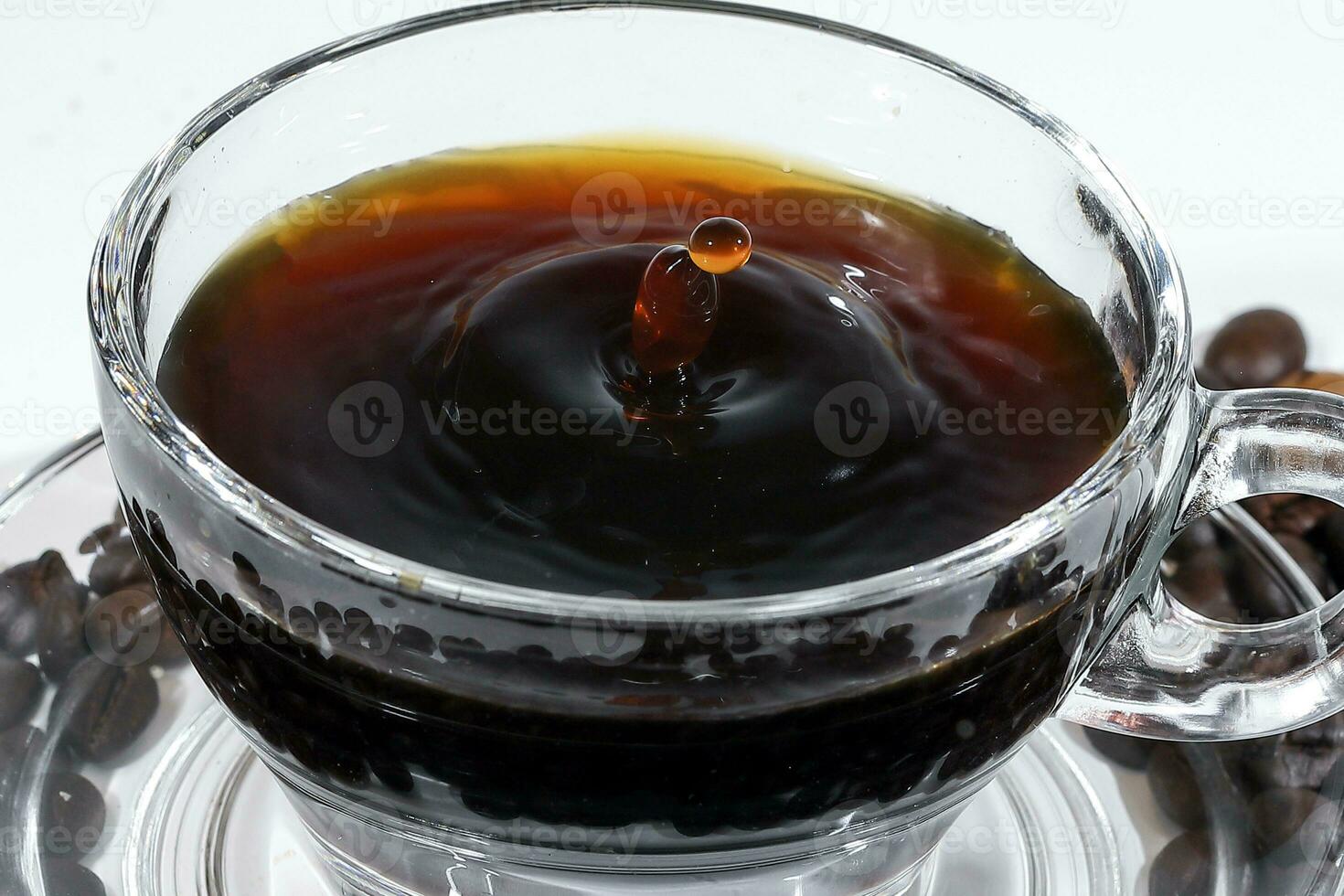 Coffee splash pillar in transparent glass cup saucer full of liquid coffee on white background photo