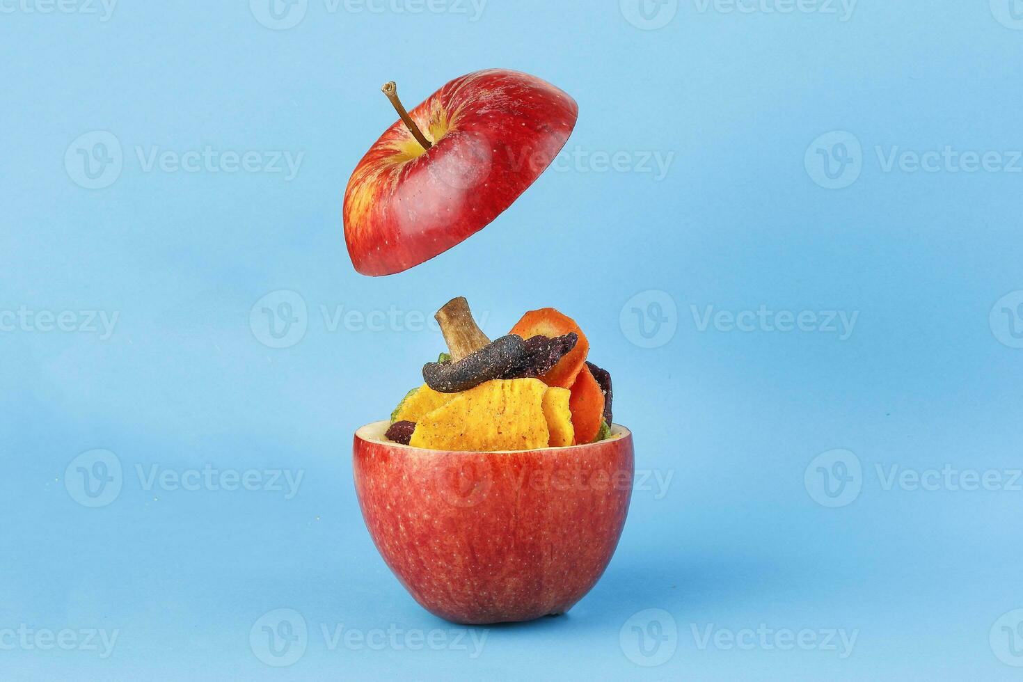 Healthy vegetable chips yellow sweet potato purple sweet potato carrot green radish green beans and shiitake mushrooms in hollow red apple blue background photo