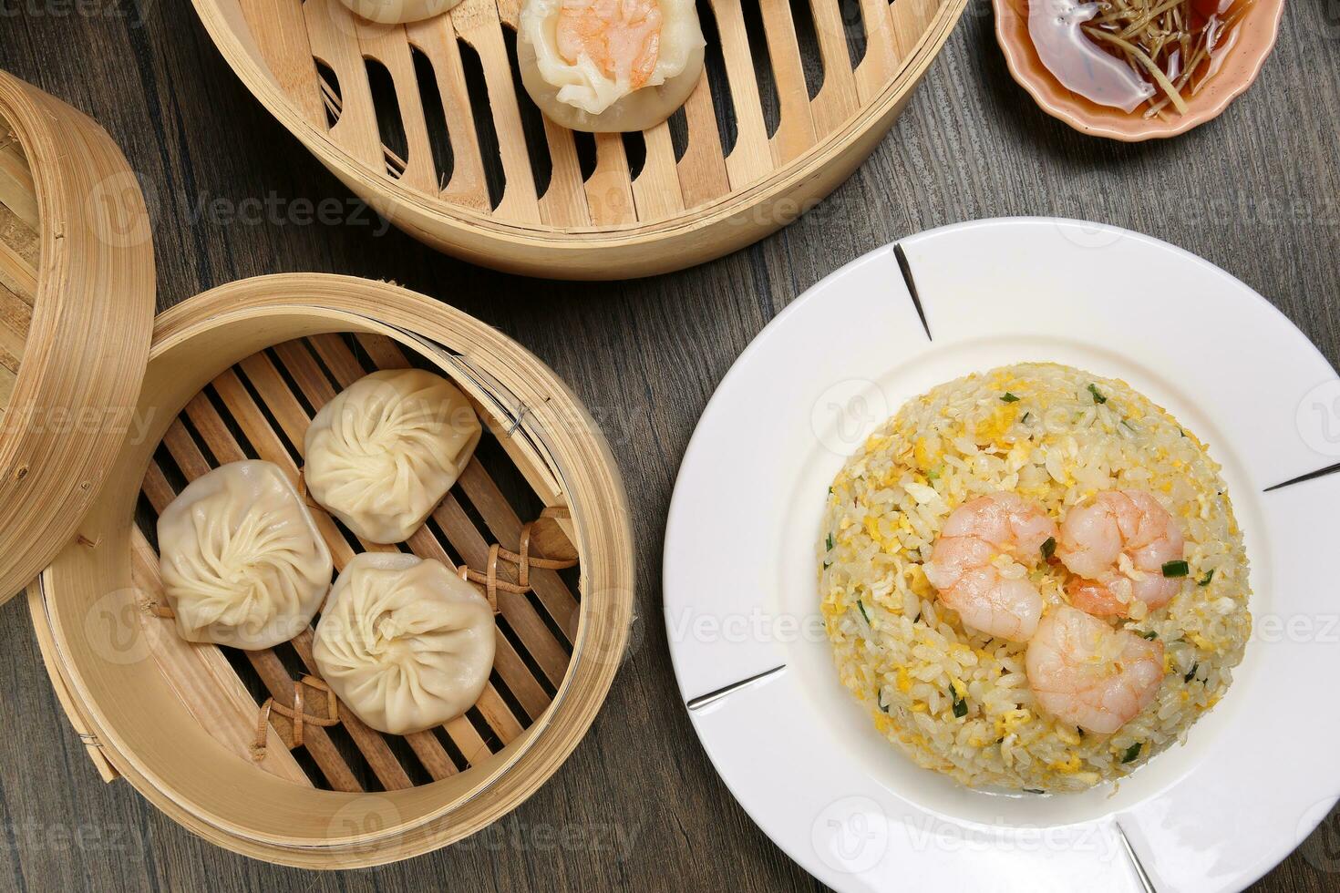 Prawn shrimp shaomai Xiao long bao dim sum dumpling chicken prawn fish seafood vegetable in bamboo steamer fried rice on plate sauce chopsticks soup spoon over rustic background photo