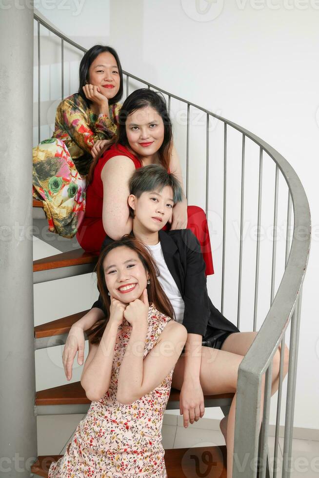 Young southeast asian woman group sitting on indoor spiral staircase happy enjoy fun look fun crazy funny photo