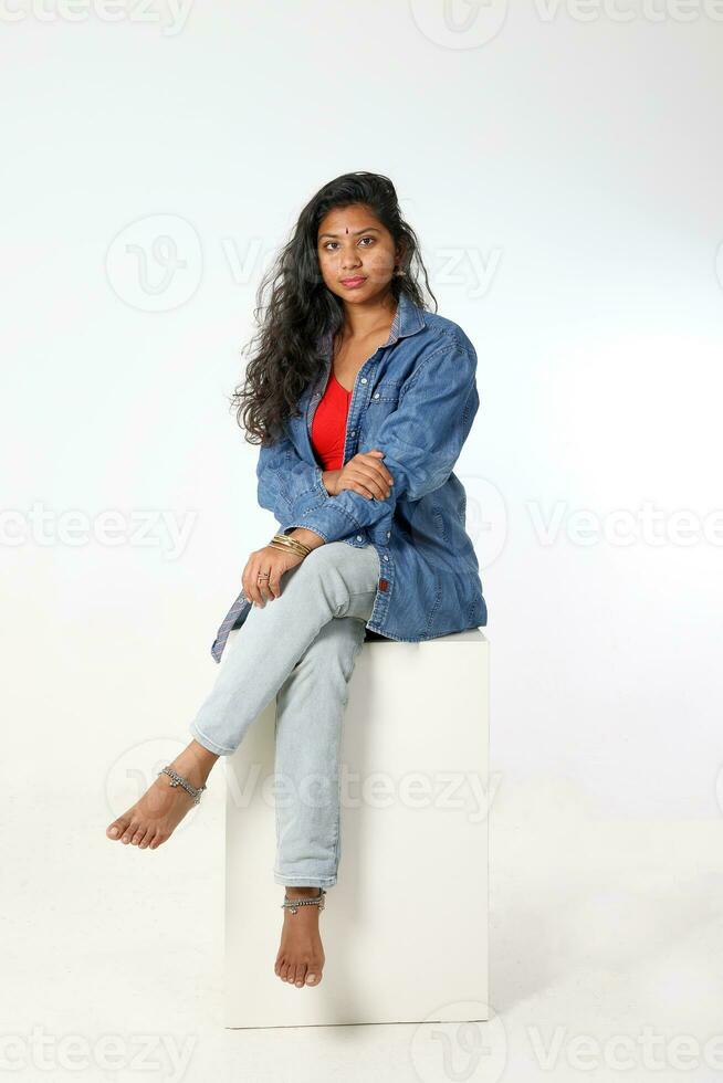 Young attractive asian Indian woman sit pose on white background look