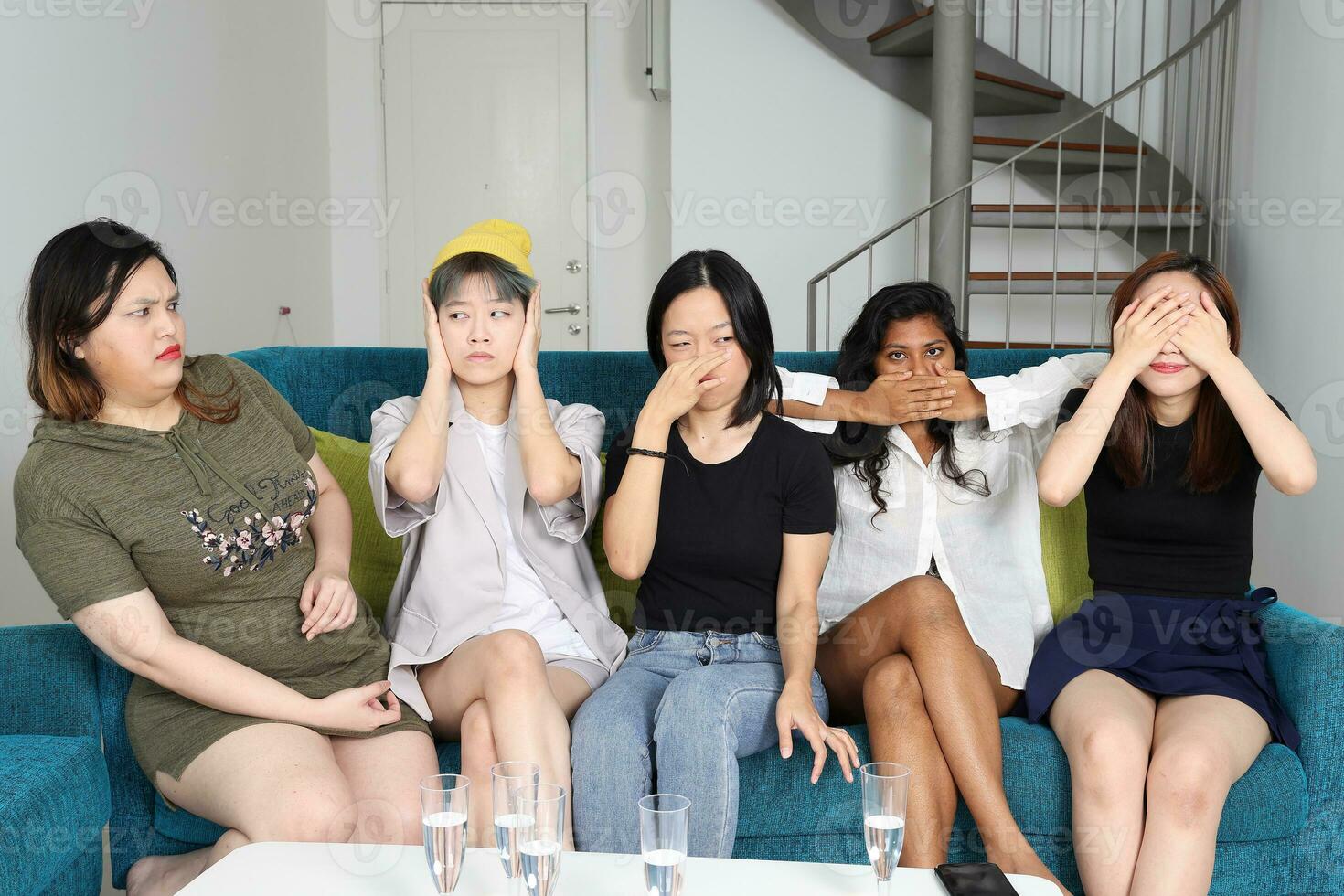 Young Asian woman group funny no smell see speak listen believe hand sign on blue living room sofa three wise monkey photo