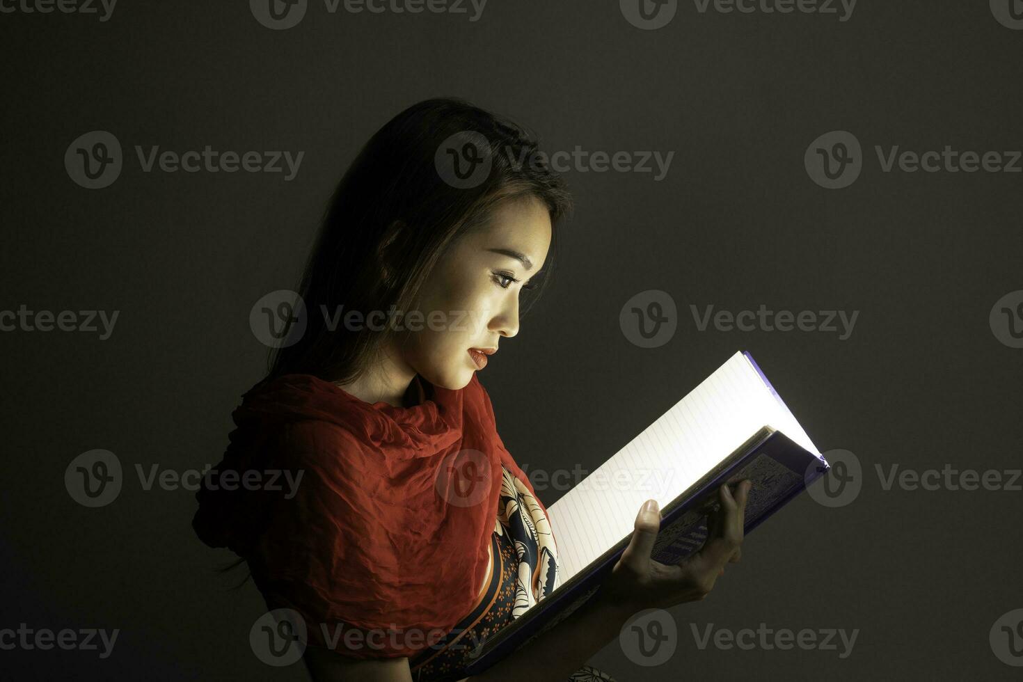 Asian woman opening mystic book box magical light dark background photo