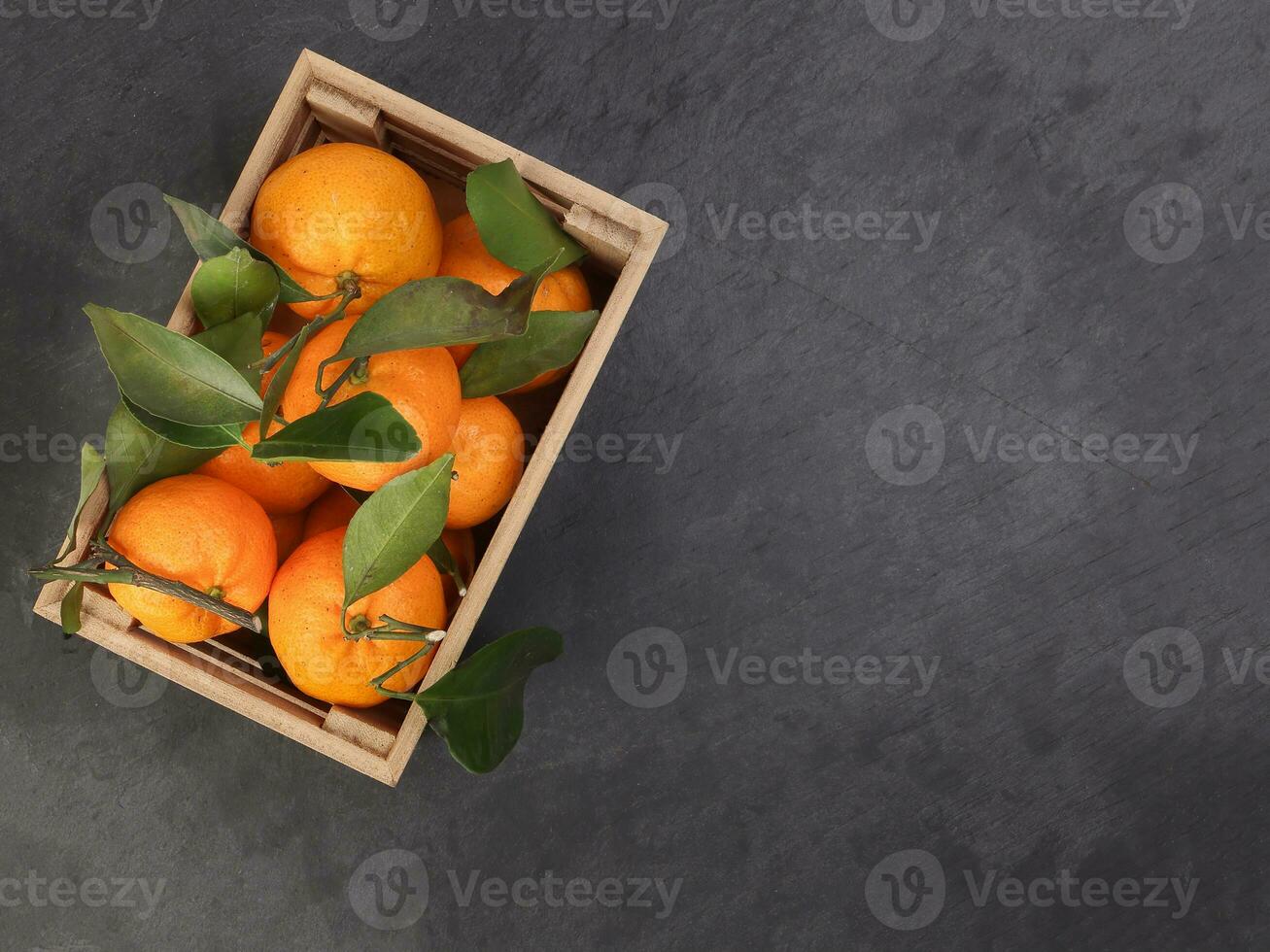 mandarin orange green leaf in wooden box crate top view copy text space on black slate marble background photo